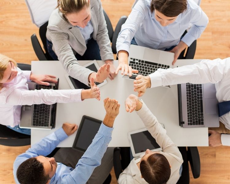 A diverse team of five professionals collaborating at a round office desk.